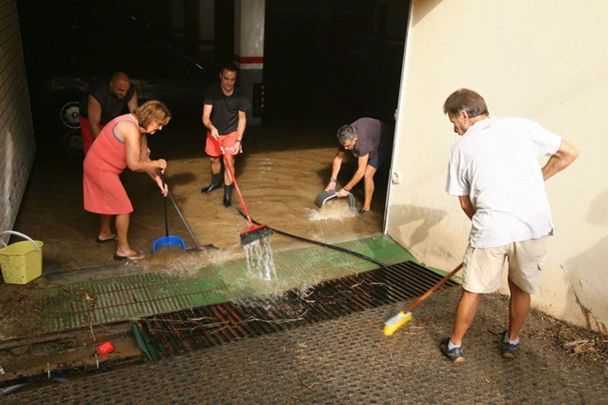 Vecinos de Segur de Calafell achican agua de un sótano inundado.