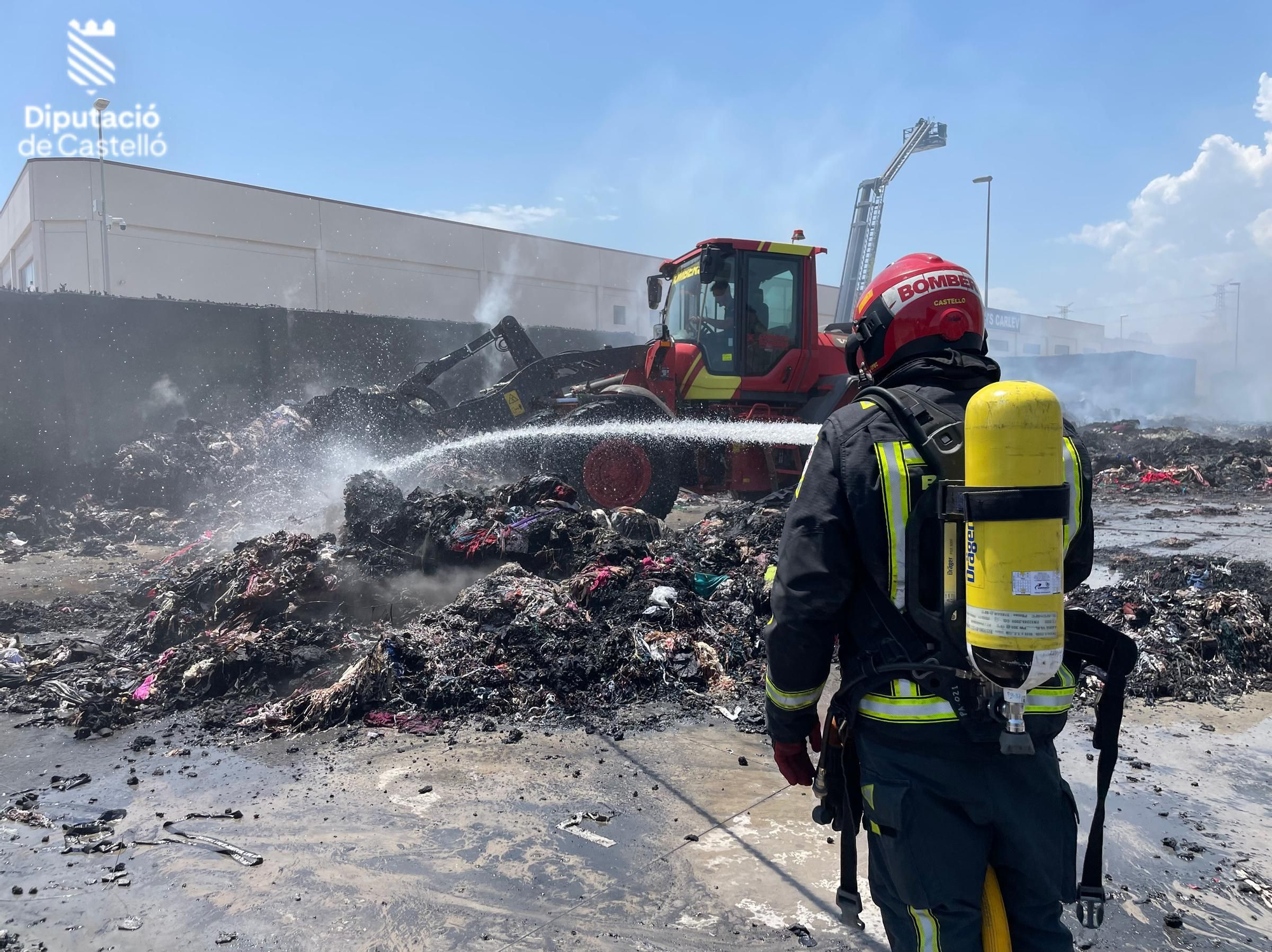 Los bomberos siguen trabajando en el en el incendio industrial de la nave de textil de Almassora