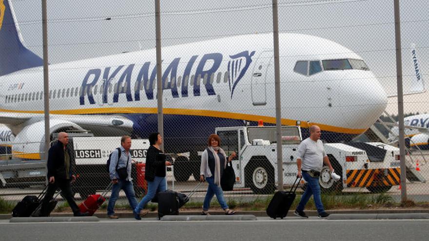 Varios pasajeros caminan con un avión de Ryanair de fondo.