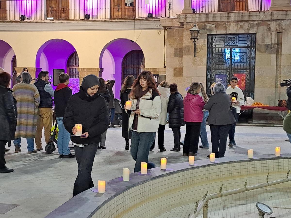 Dos jóvenes llevan una vela en la plaza Mayor de Nules.