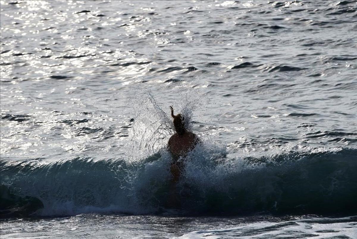 Una mujer entra en el agua en la playa de la Barceloneta.