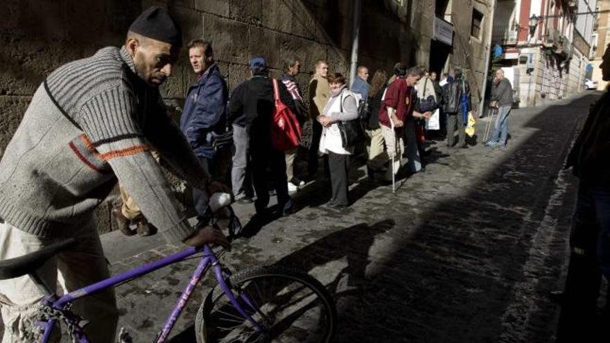 Decenas de personas sin hogar hacen cola a espaldas de la concatedral para recoger un bocadillo y un par de zumos.