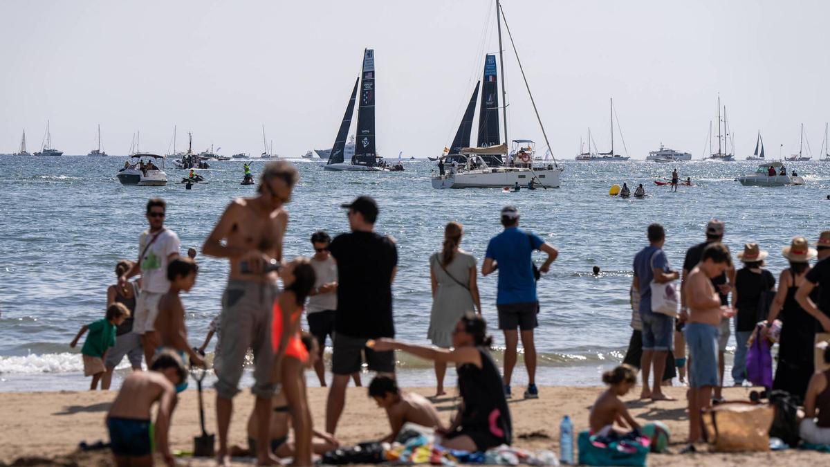 Ambiente en la playa de los aficionados y bañistas que observan la competicion con prismaticos y pantallas gigantes.