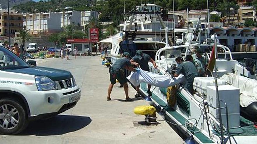 Efectivos de la Guardia Civil bajan de la embarcación uno de los cadávares encontrados ayer en el mar.