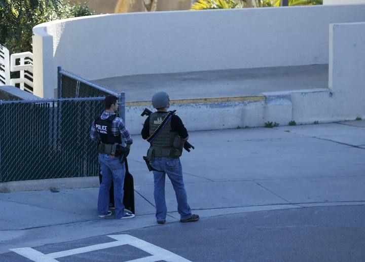 Law enforcement personnel stand near a parking garage adjacent to Building 26 at the Naval Medical Center in San Diego