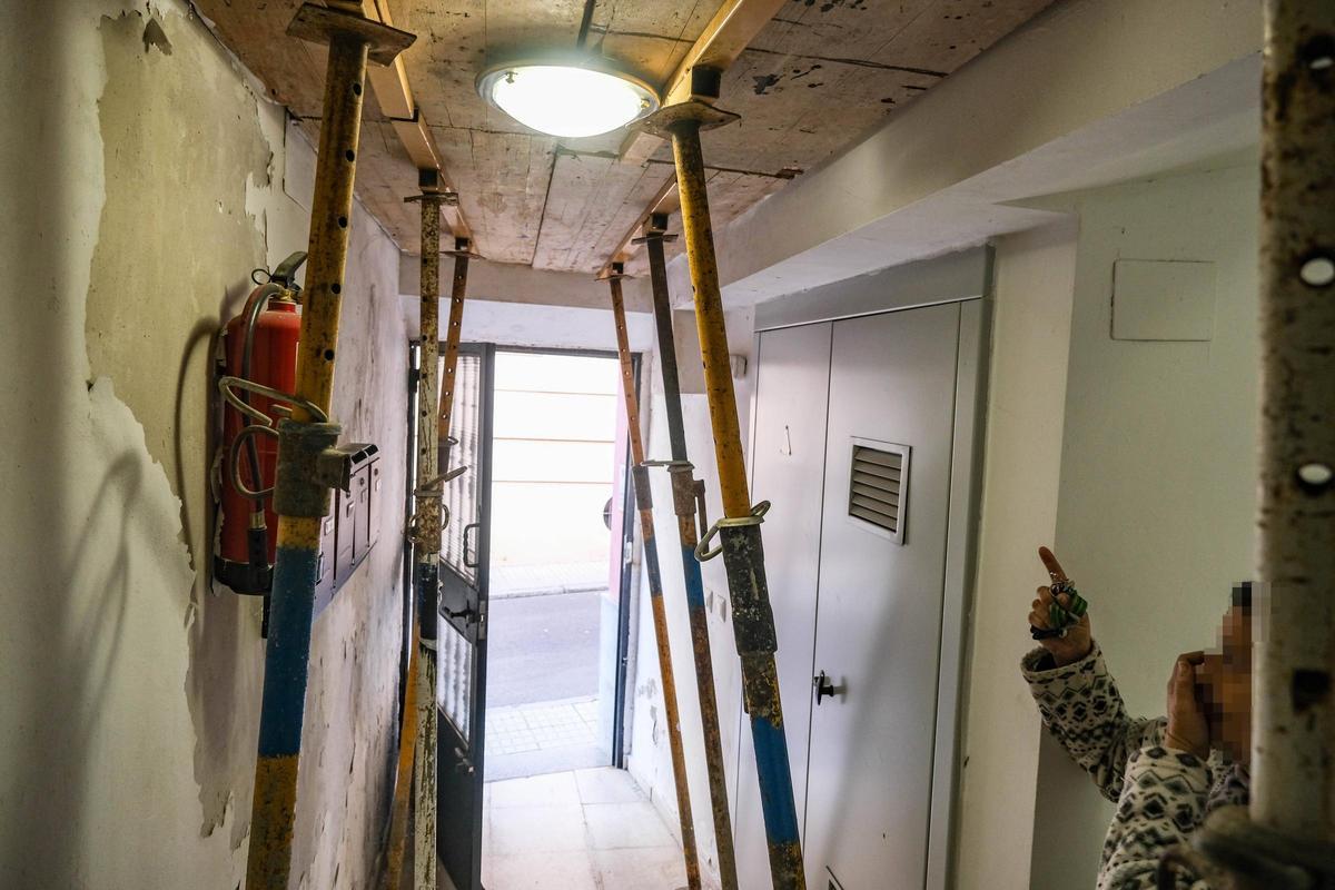 Vecina afectada de la calle Doblados señalando el portal apuntalado de su edificio ayer en Badajoz.