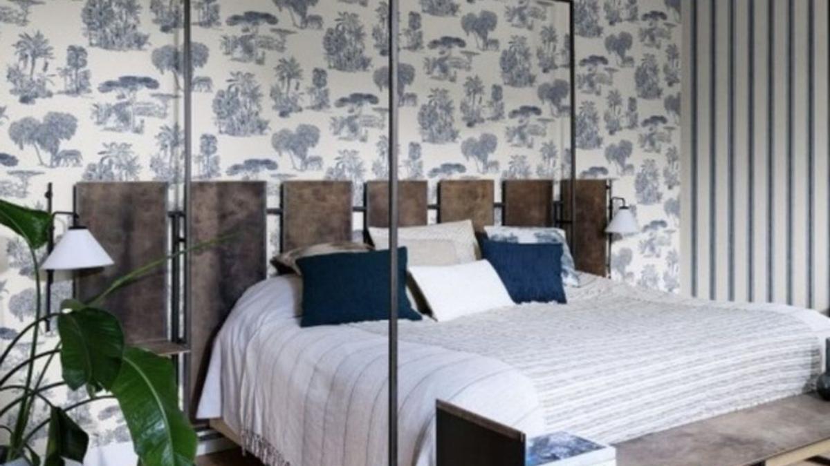 Un dormitorio con papel floral en la pared. | PR