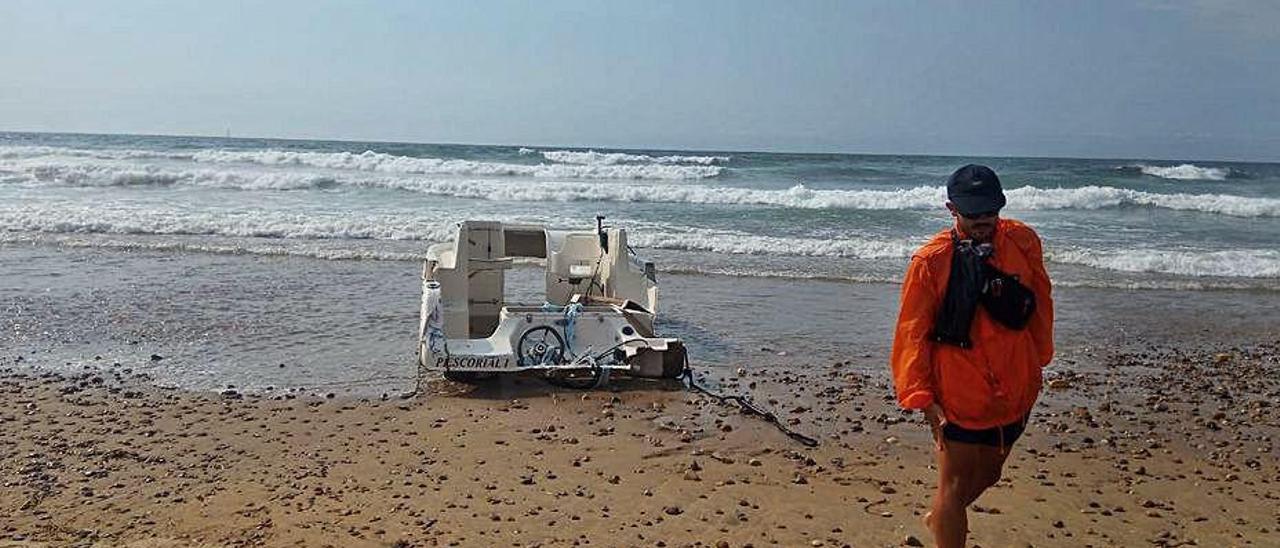 Un socorrista traslada la embarcación después de que el mar la arrastrara hasta la orilla en Xagó.