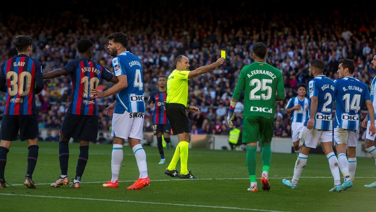 Mateu Lahoz enseña una cartulina amarilla a Brian Oliván en el derbi del Camp Nou.