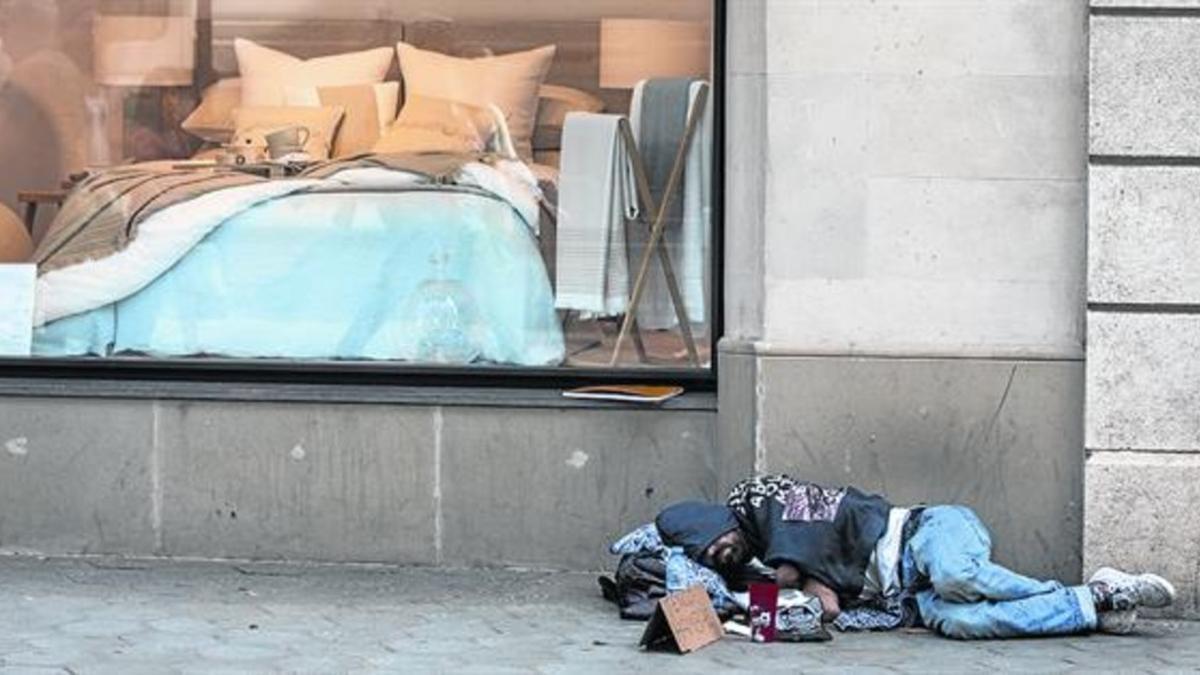 Desigualdad 8Un sintecho duerme junto al escaparate de una tienda de ropa de hogar, en el paseo de Gràcia.