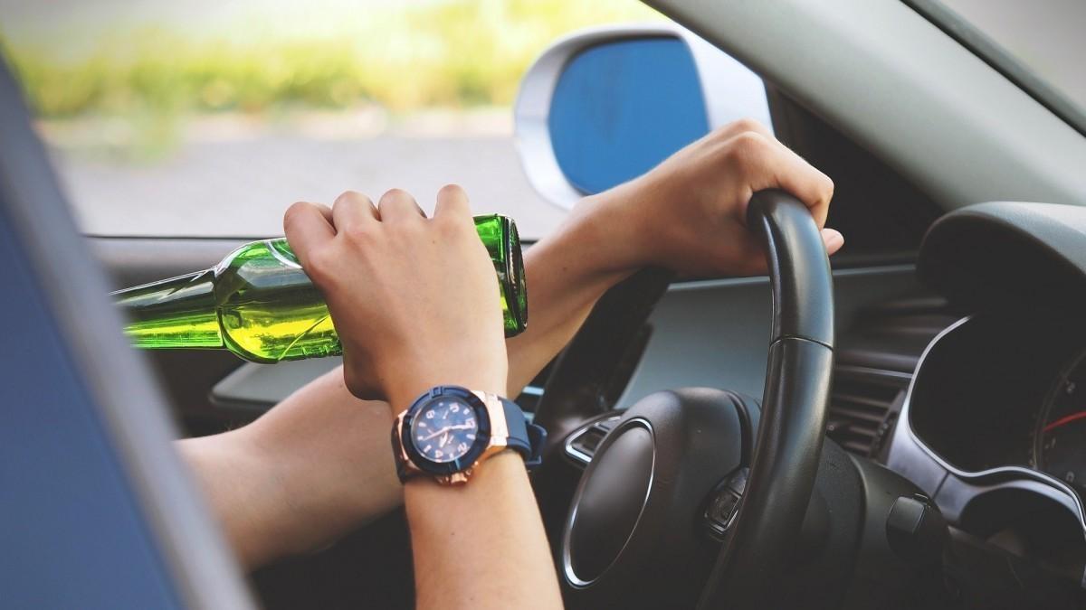 Imagen de archivo de una persona al volante con una cerveza en la mano.