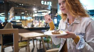 Una mujer come un trozo de tarta en una cafetería.