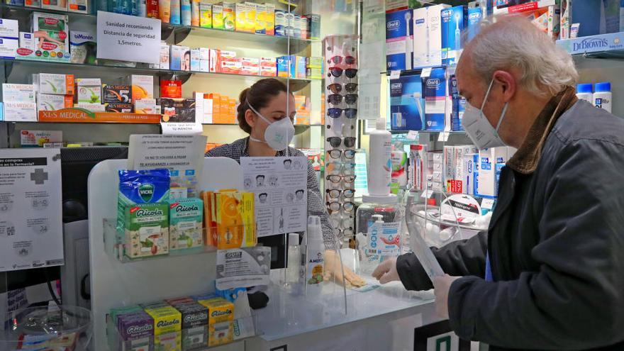 Un hombre recibe sus mascarillas en la farmacia.