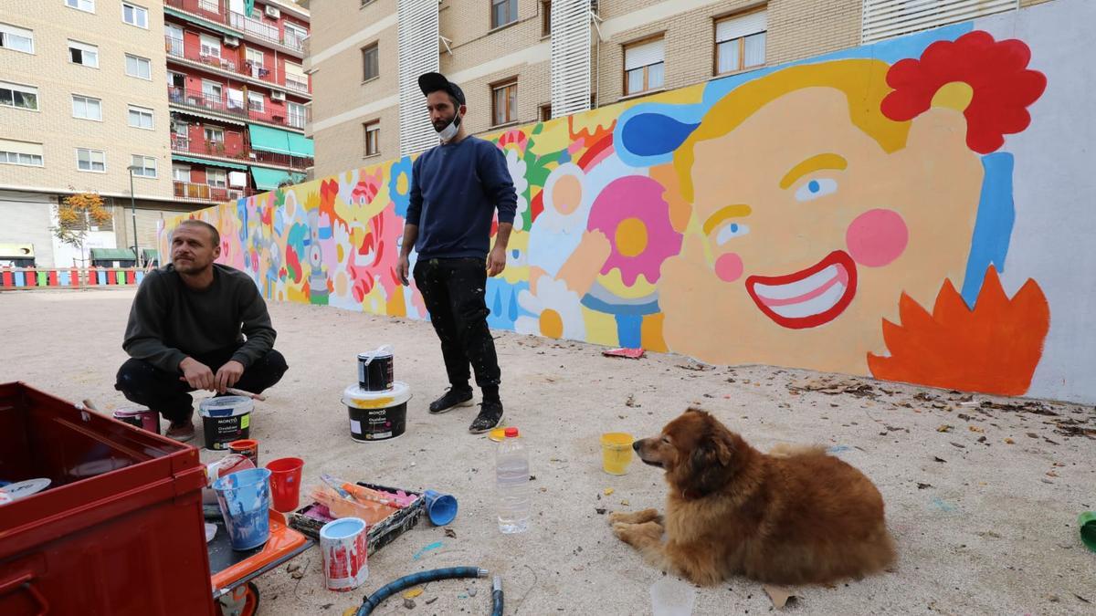 Los artistas Geco y Asis Percales, este martes junto al mural que están pintando en la calle Jesús de Zaragoza.