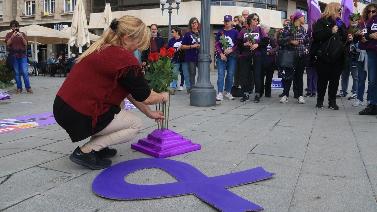 Una dona col·loca una rosa per homenatjar a les víctimes de violència masclista, en l'acció reivindicativa a Tarragona amb motiu del 25-N