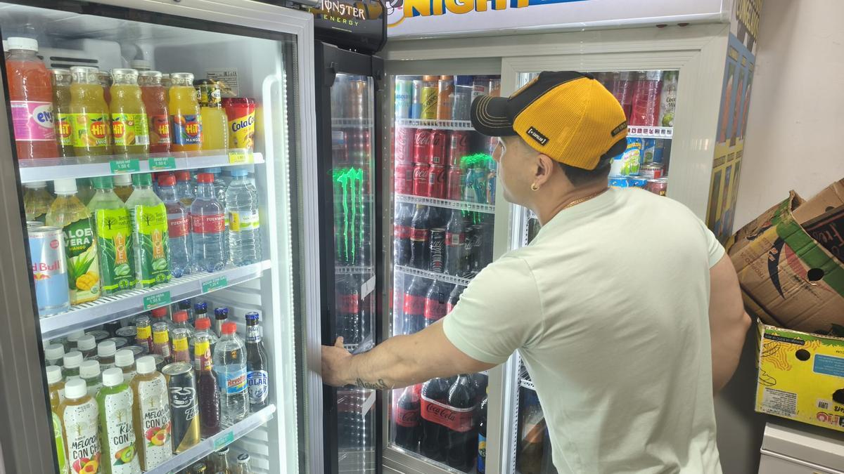 Alejandro Barbosa abriendo la nevera de bebidas energéticas de su establecimiento.
