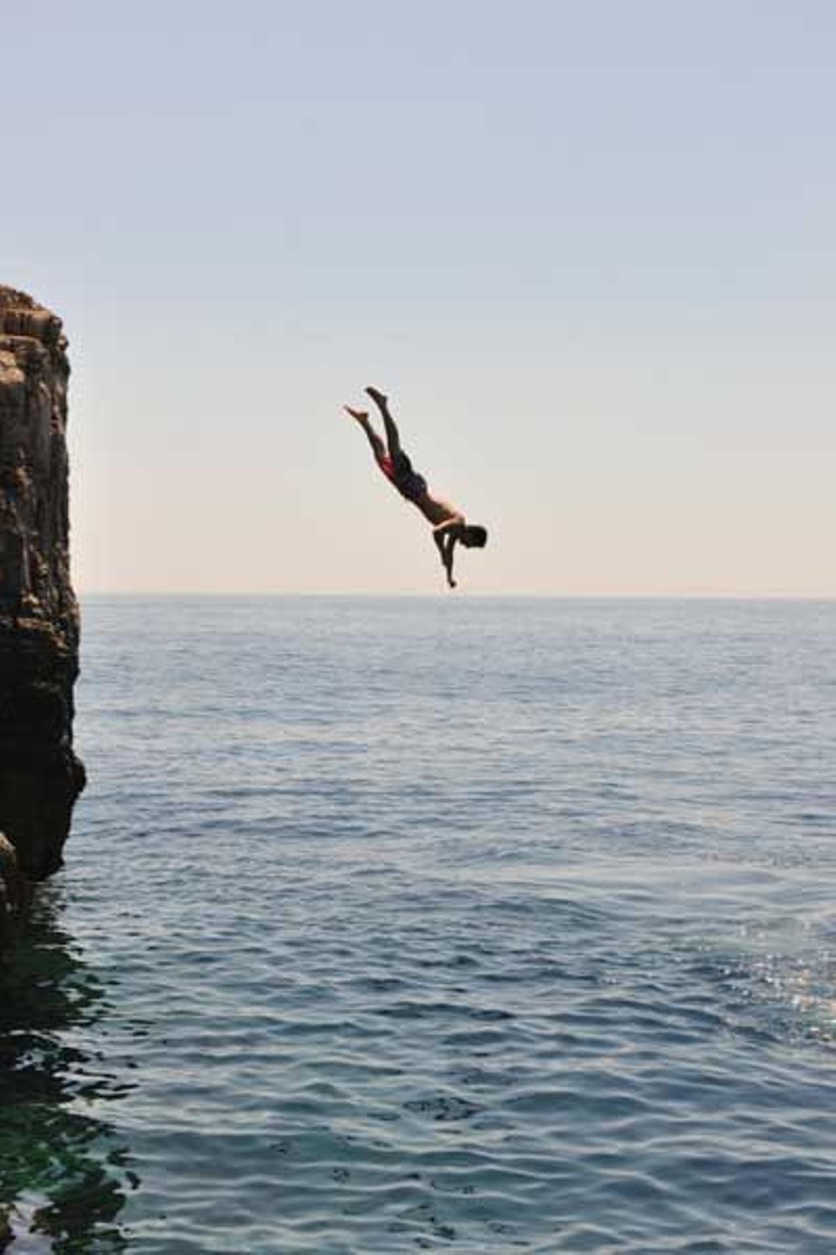 Un bañista se precipita al mar desde un pequeño acantilado en la isla de Lokrum