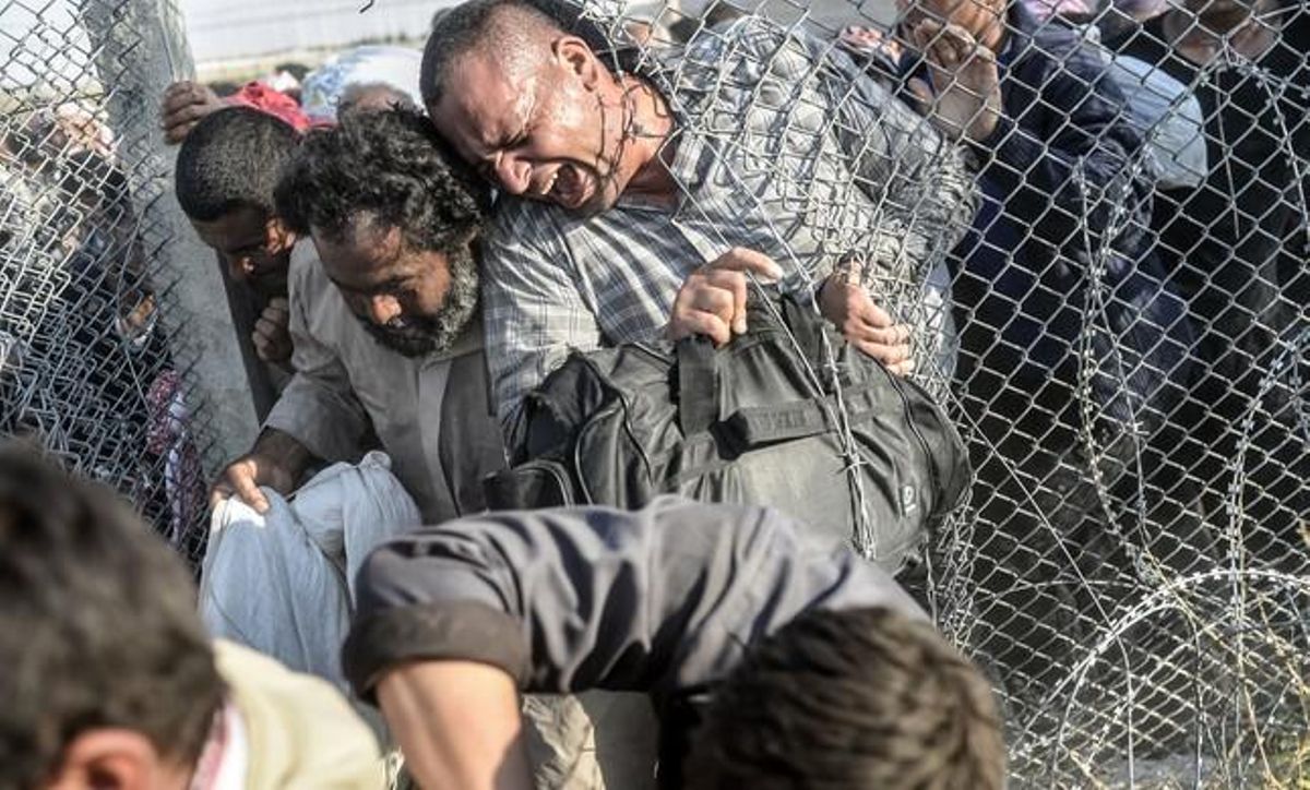 Un refugiat sirià intenta passar per un forat en el filat de ganivetes.