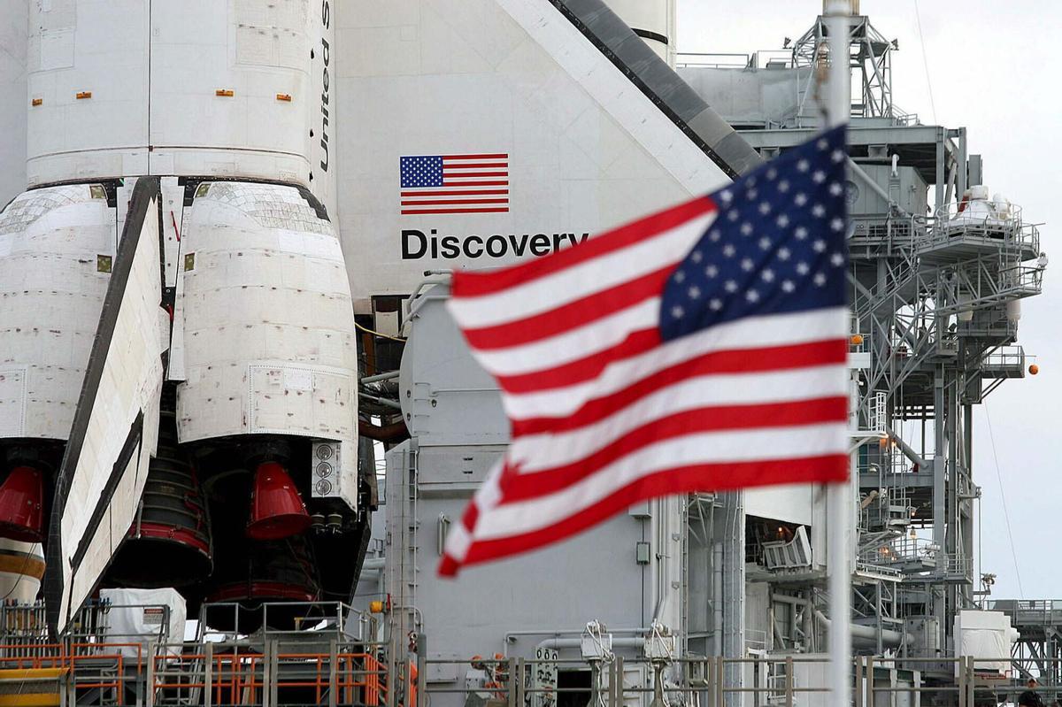 Una bandera estadounidense ondea delante del transbordador espacial "Discovery" en el Centro Espacial Kenedy en Cabo Cañaveral, Florida, EEUU.