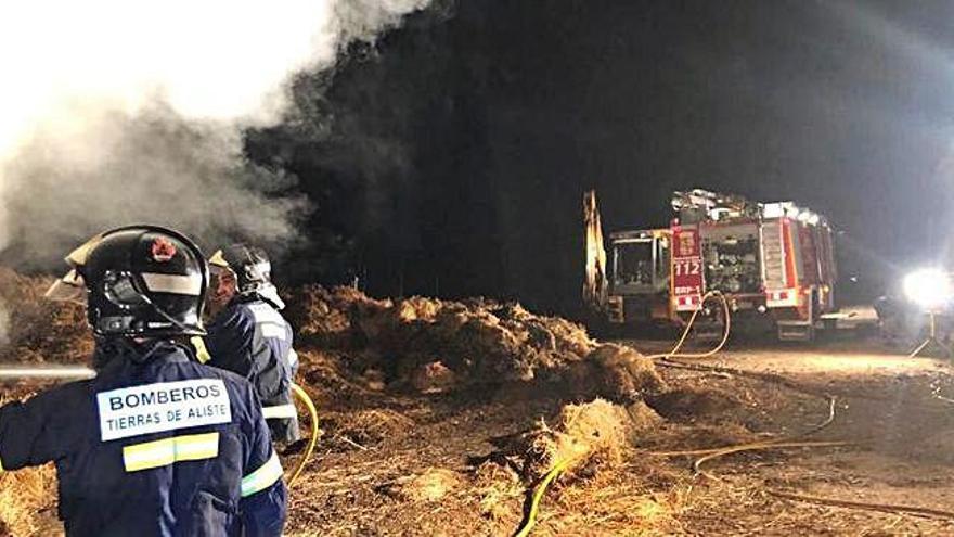 Dos bomberos apagan las llamas.