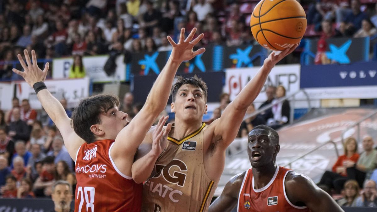 Juani Marcos (c), del Basquet Girona, entra a canasta defendido por Max Gaspá (i), del Baxi Manresa, durante el partido de la jornada 28 de la Liga Endesa.