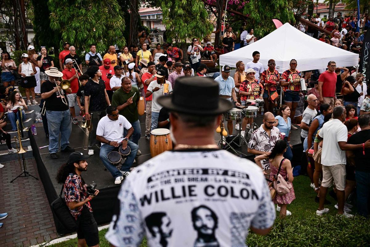 A man wearing a T-shirt depicting the late Willie Colon conducts a group of trombonists during a tribute to the US musician in Panama City on April 12, 2026. US musician Willie Colon died in Bronxville, New York, on February 21, 2026, at the age of 75.