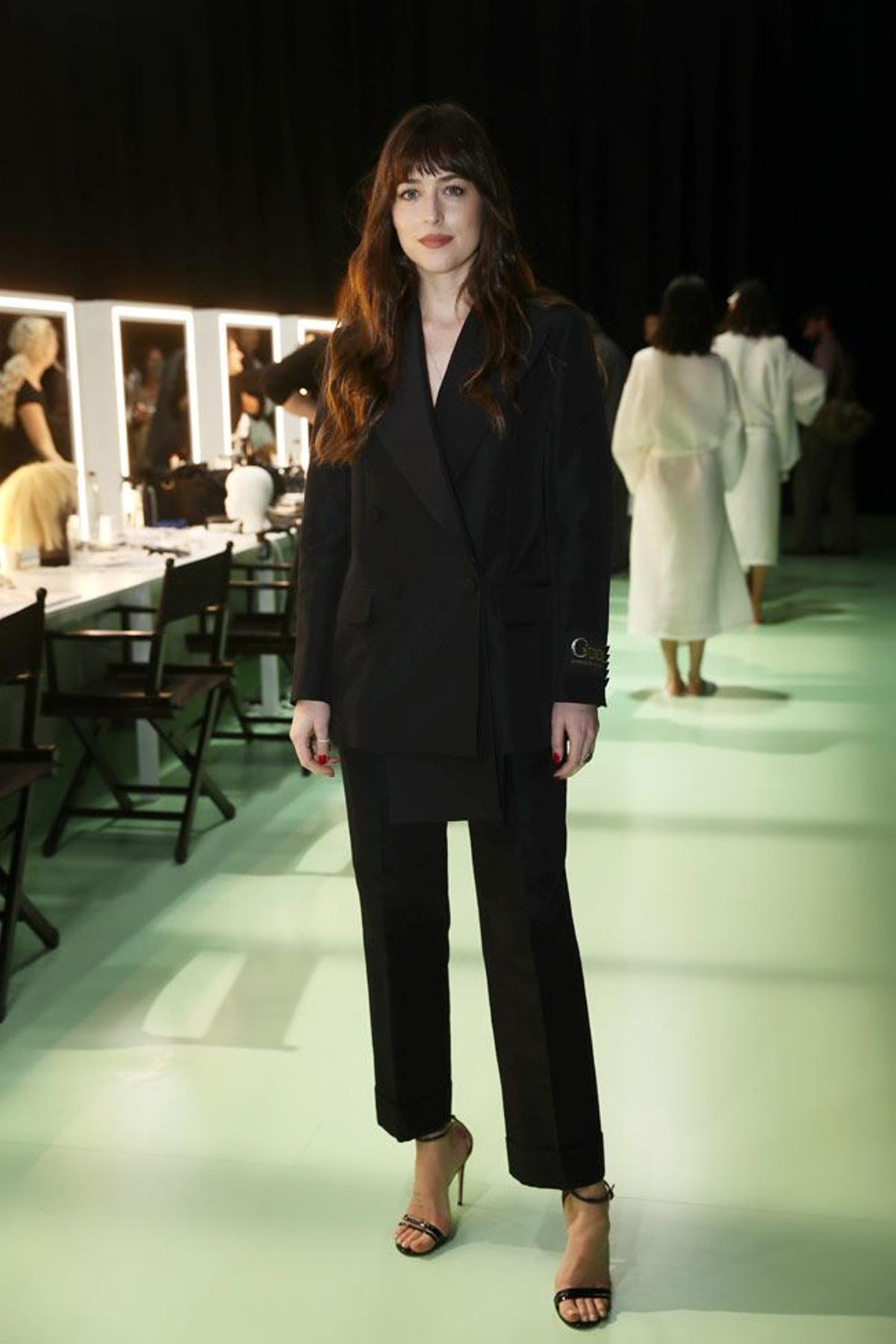 Dakota Johnson con traje negro de chaqueta y pantalón en el desfile de Gucci
