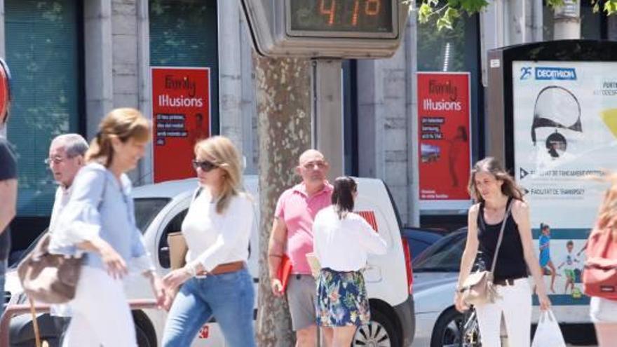 Un grup de persones camina sota la intensa calor del dia, aquesta setmana a la ciutat de Girona.