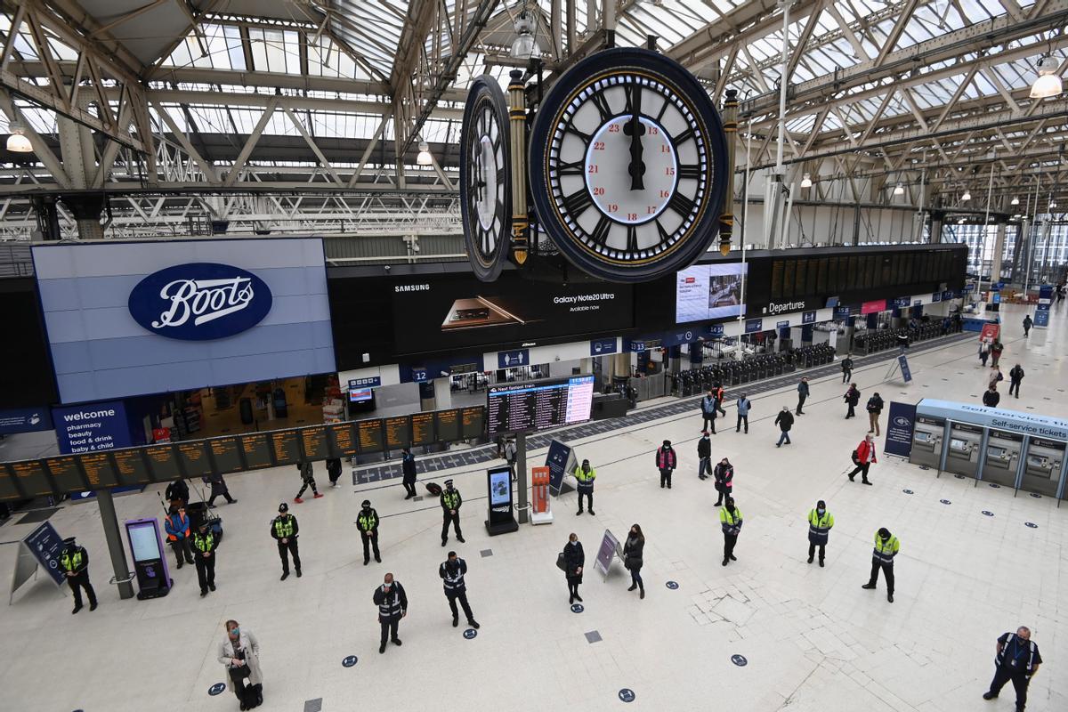 Viajeros y trabajadores de la estación de Waterloo, en Londres, guardan un minuto de silencio en recuerdo de las víctimas mortales del covid en el aniversario del primer confinamiento británico.