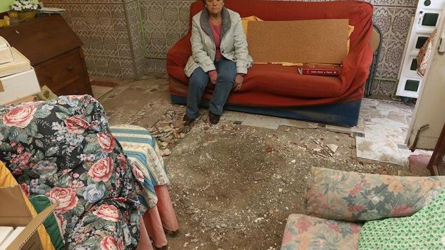 La imagen muestra a Josefa sentada en el sofá de su salón, justo donde reventó la tubería.Las losas del suelo salieron volando por los aires con la fuerza del agua.