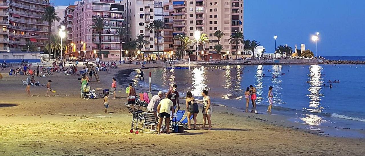 Playa del Cura de Torrevieja, repleta de bañistas, incluso con mesas y sillas, a las 22 horas, cuando el horario de cierre es a las 20.30 horas.