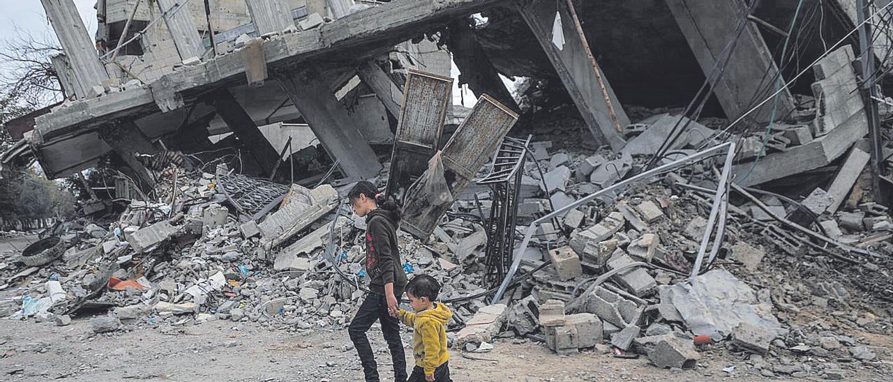 Dos niños pasan junto a un edificio destruido por el Ejercito Israelí en Gaza.