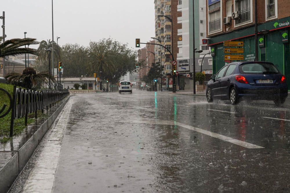 El río Guadalmedina crecido con agua y calles del Centro y el entorno del cauce, desiertas bajo la lluvia, la estampa de este martes 31 de marzo.