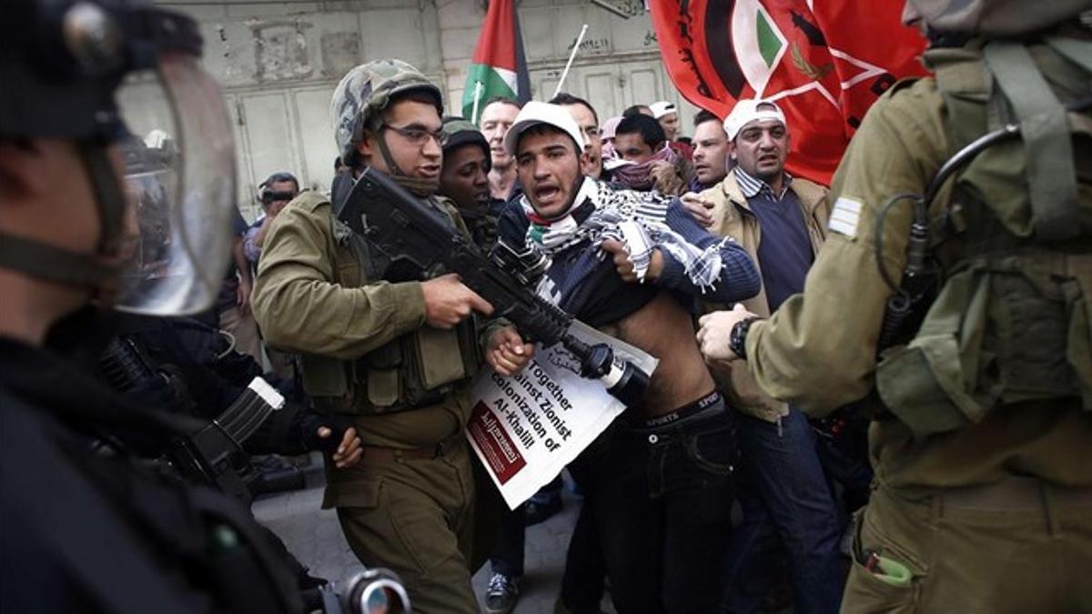 Palestinos y soldados israelís forcejean en el centro de Hebrón, este viernes.