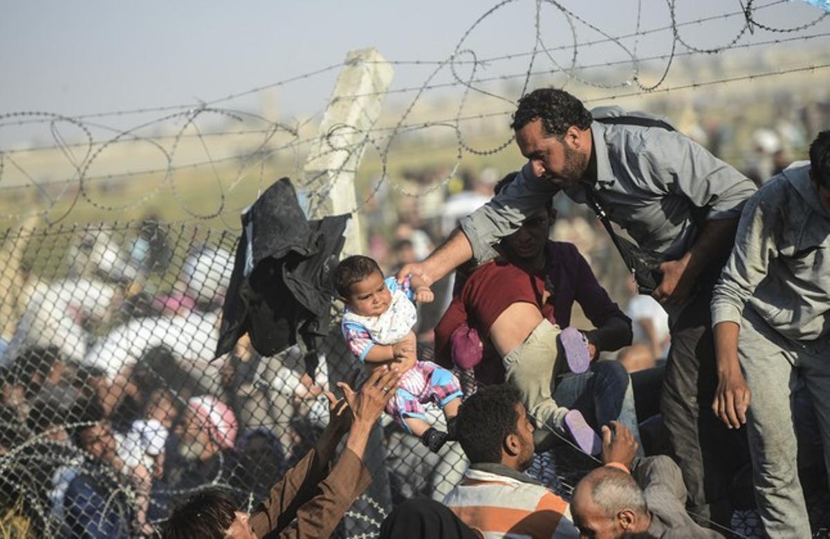 Refugiados sirios intentan hacer cruzar a Turquía a un bebé a través de la alambrada.