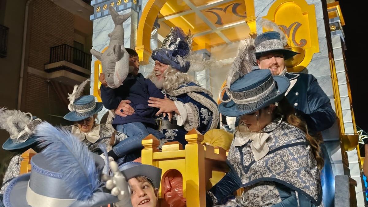 Uno de los Reyes Magos de Lucena entrega juguetes a un niño durante la Cabalgata.