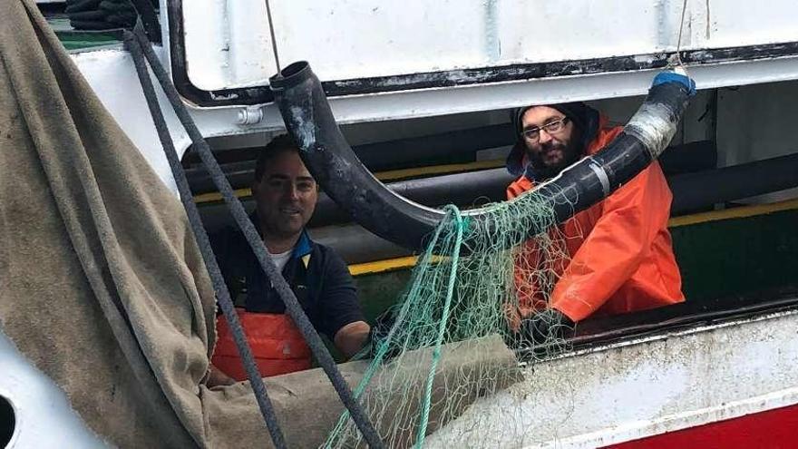 Dos de los pescadores de centollo del puerto de O Grove depositando los &quot;miños&quot; en su barco. // Muñiz