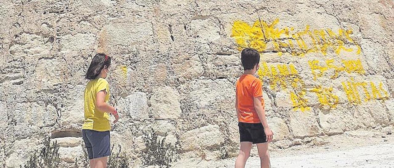 Dos niños pasan ayer por el torreón pintado.