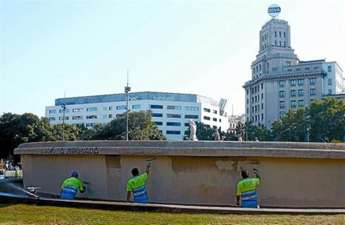 A dalt, la font de plaça de Catalunya plena de pintades. A sota, operaris pinten novament la font, ahir.