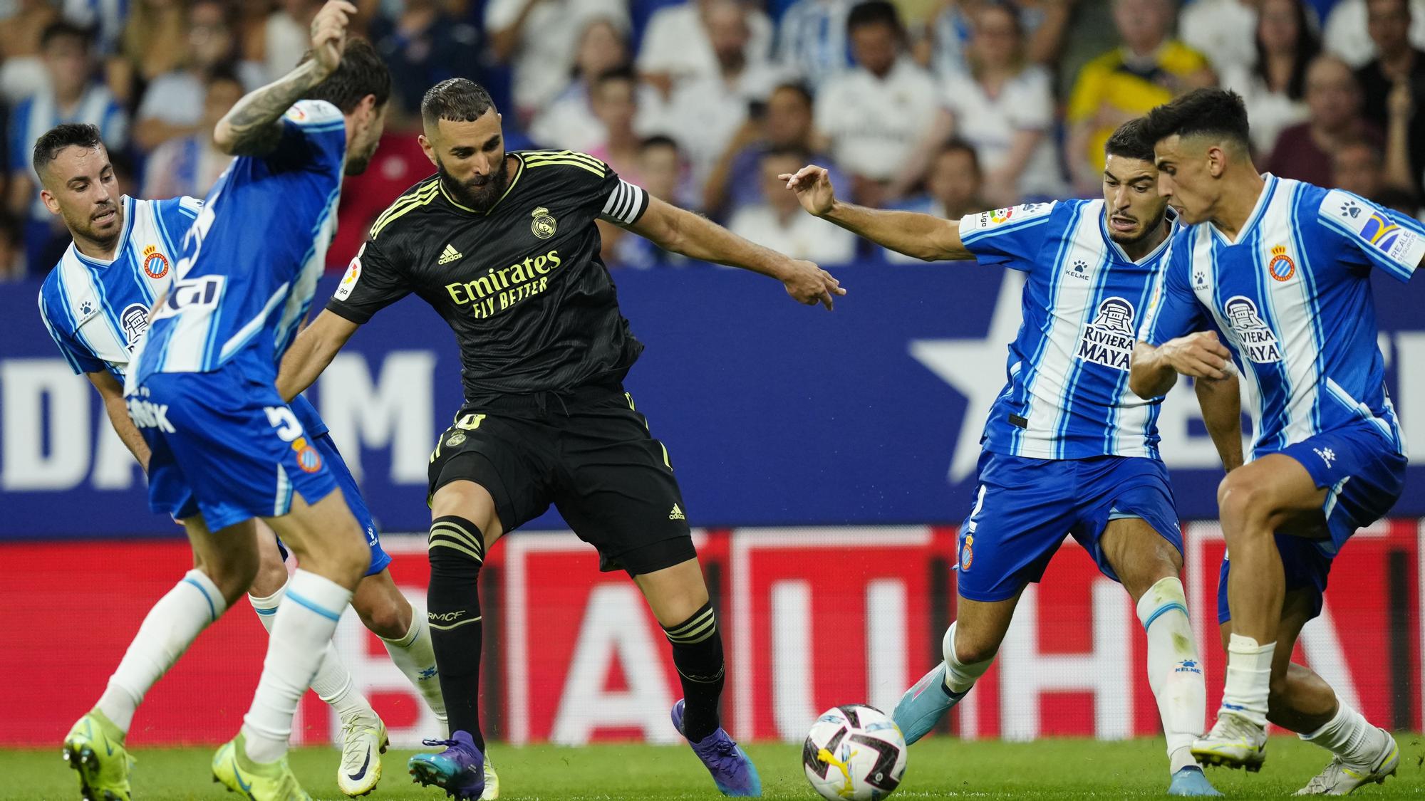 El delantero del Real Madrid Karim Benzema (c) se escapa de los jugadores del RCD Espanyol, durante el partido de la tercera jornada de LaLiga que RCD Espanyol y Real Madrid juegan hoy domingo en el RCDE Stadium. EFE/Enric Fontcuberta