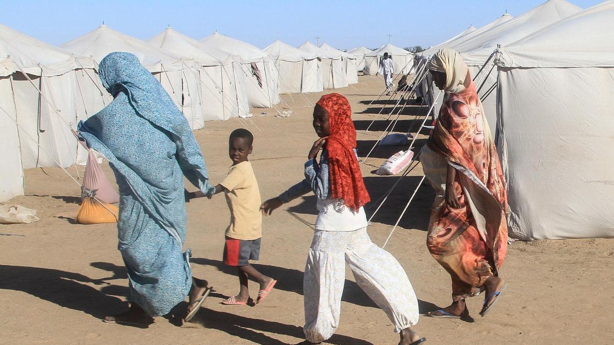 Sudaneses que huyeron de El-Fasher caminan junto a tiendas de campaña en el campamento de desplazados de Al-Afad, en la ciudad de Al-Dabba, al norte de Sudán, el 15 de noviembre de 2025. Desde su inicio en abril de 2023, la guerra entre el ejército sudanés y las Fuerzas de Apoyo Rápido (FAR), un grupo paramilitar, ha causado la muerte de decenas de miles de personas y el desplazamiento de casi 12 millones. A finales de octubre, el grupo paramilitar tomó el control de El-Fasher, poniendo fin a un cruento asedio de 18 meses por este centro estratégico en la región de Darfur, al oeste de Sudán, marcado por informes de asesinatos en masa y violencia sexual.