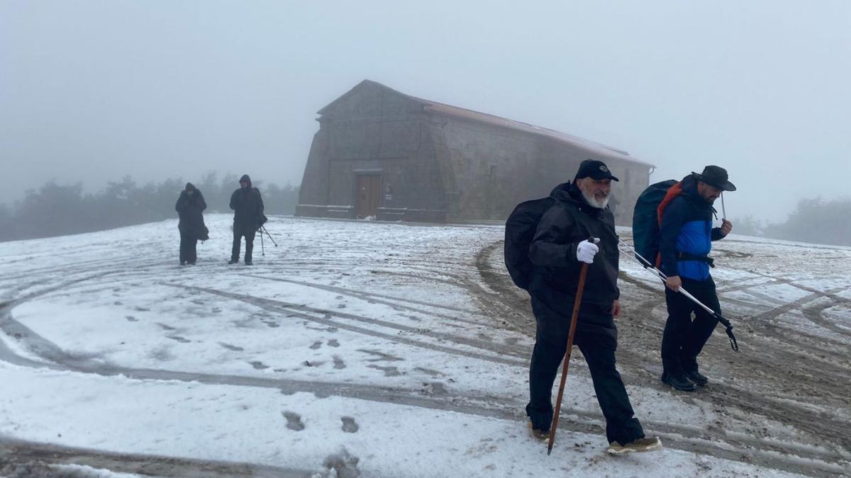 Cuatro peregrinos descienden tras visitar la capilla en la cumbre de Monte do Faro.