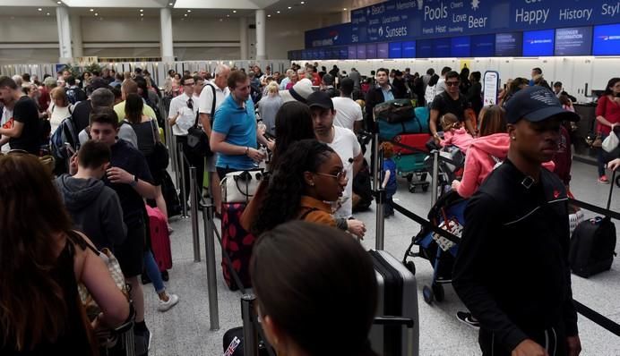 People queue with their luggage for the British ...