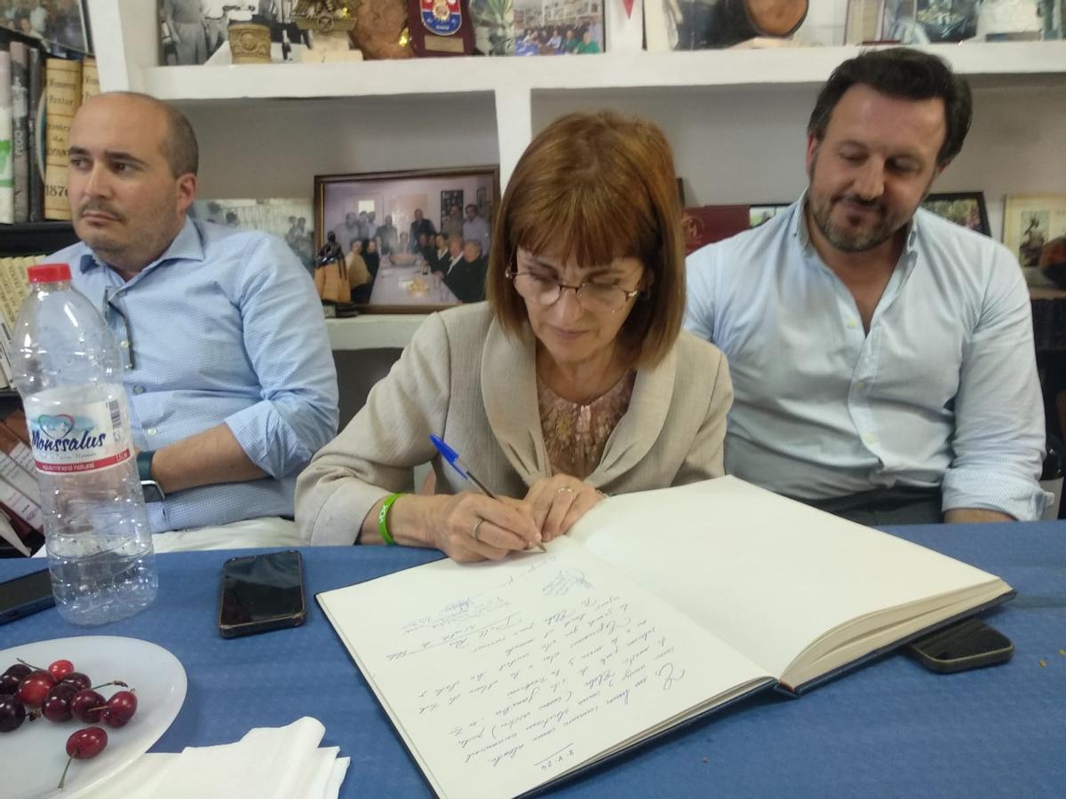 Aurora Rodil firma en el libro de la asociación de Amigos del Arroz con Costra de Elche