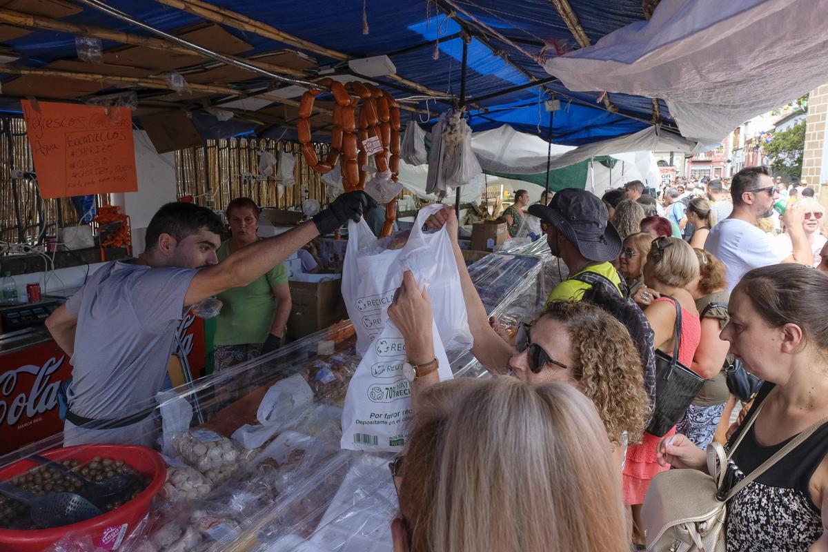 Uno de los puestos de venta de productos ubicado en la trasera de la basílica de ElPino registra una gran cola de clientes para comprar el bocadillo de chorizo de Teror.