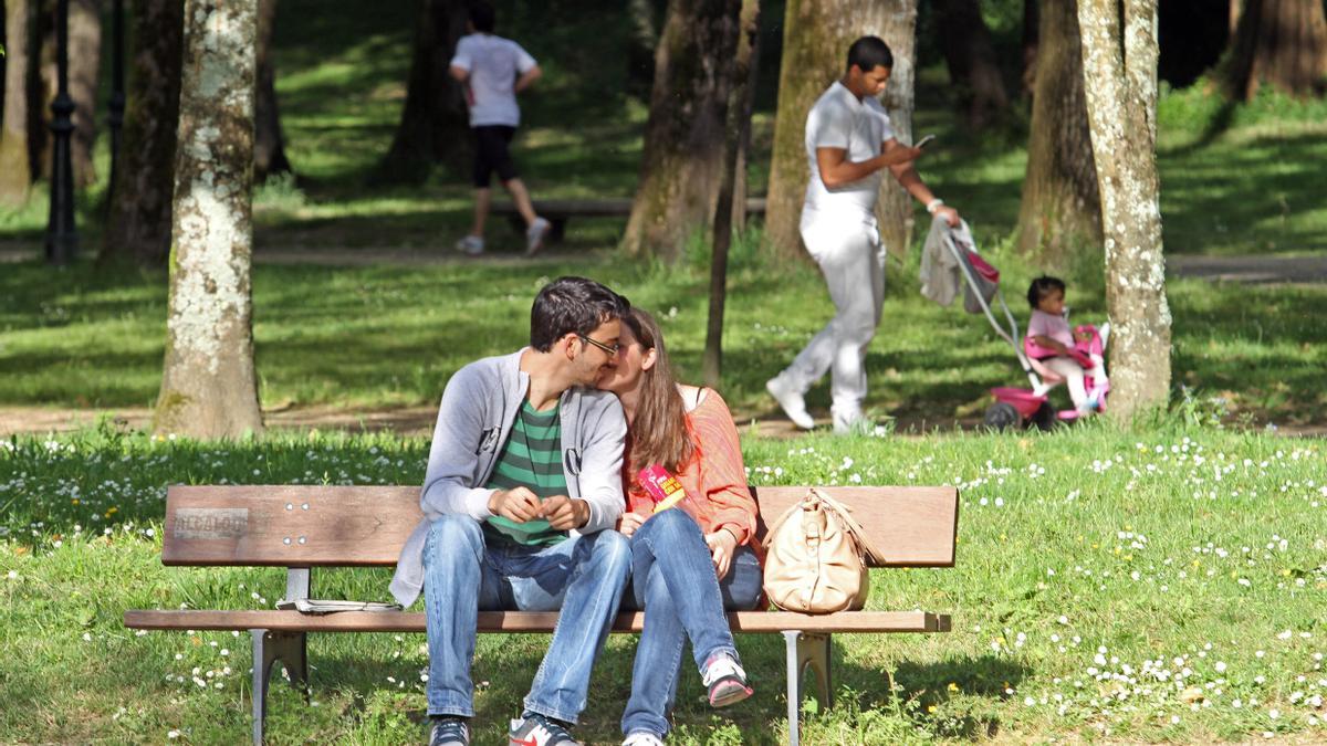 Una pareja se hace carantoñas en un parque.