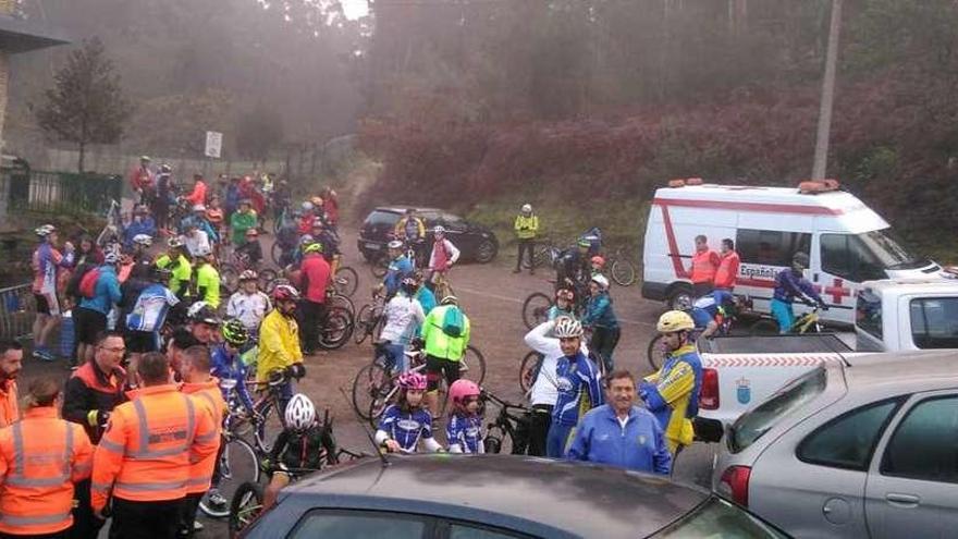 Ciclistas y miembros de seguridad, con la Agrupación de Emergencias y la ambulancia, en el momento de comenzar la marcha. // G.N.