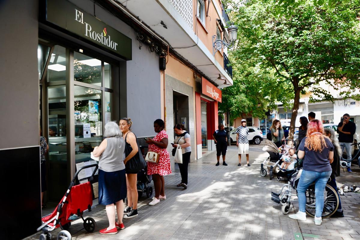 Varias personas de diferentes edades hacen cola para comprar en una casa de comidas de València, esta semana.