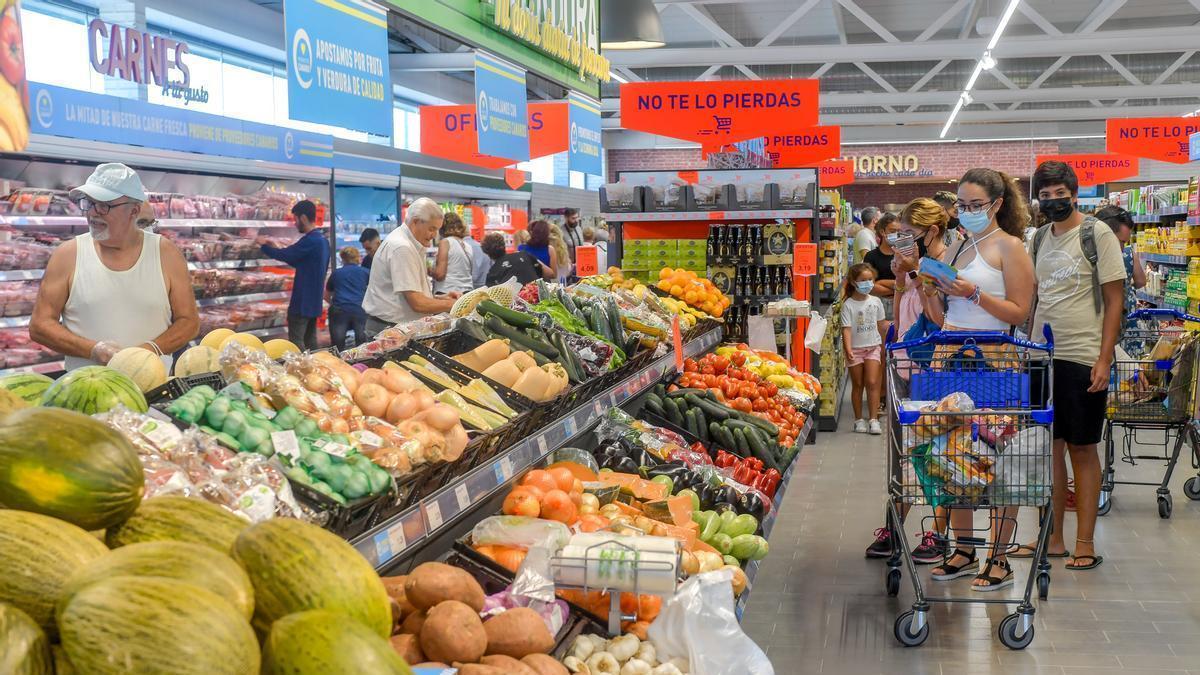 Varias personas realizan sus compras en un supermercado.