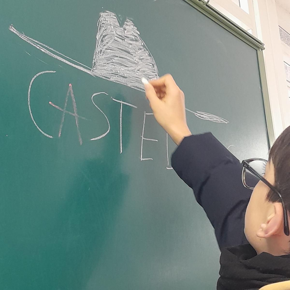 Un alumno do IES de Rianxo debuxando na pizarra o emblemático sombreiro de Castelao.